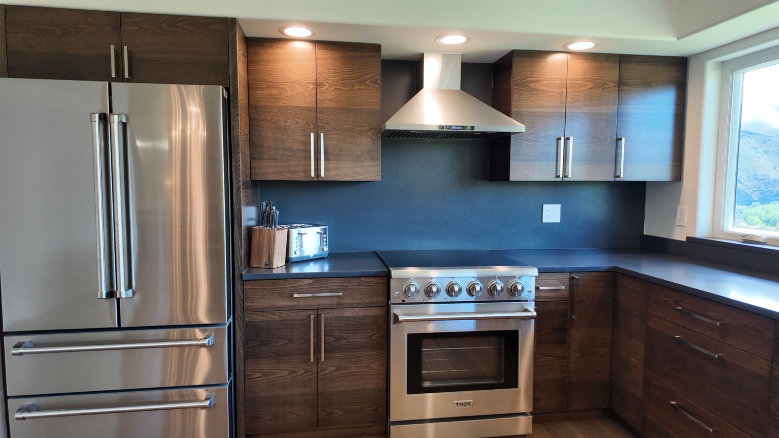 Chef's kitchen with a stainless Thor electric range, French-door refrigerator and dark wood cabinetry