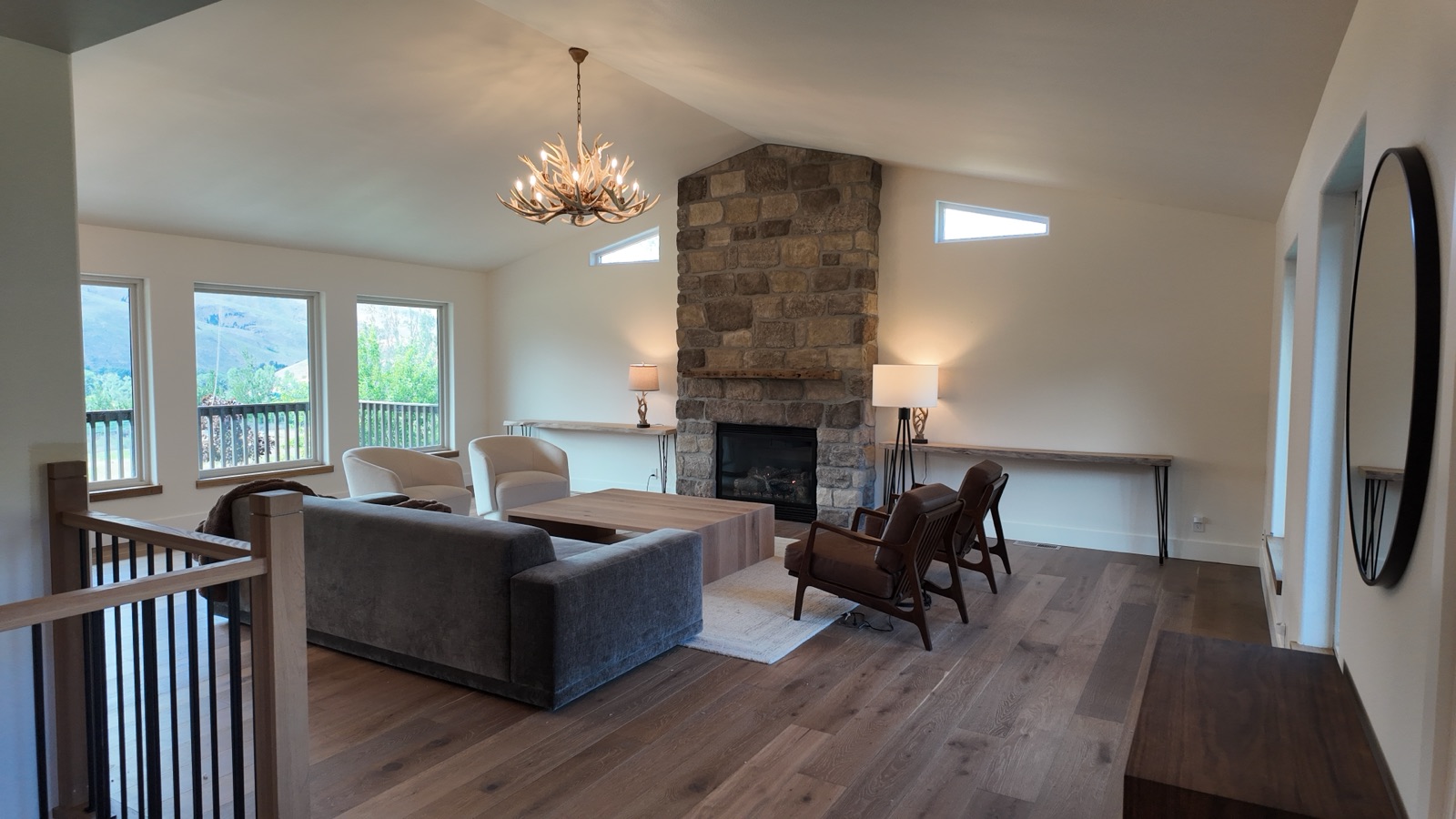 Vaulted great room with floor-to-ceiling stone gas fireplace, antler chandelier and canyon-view windows