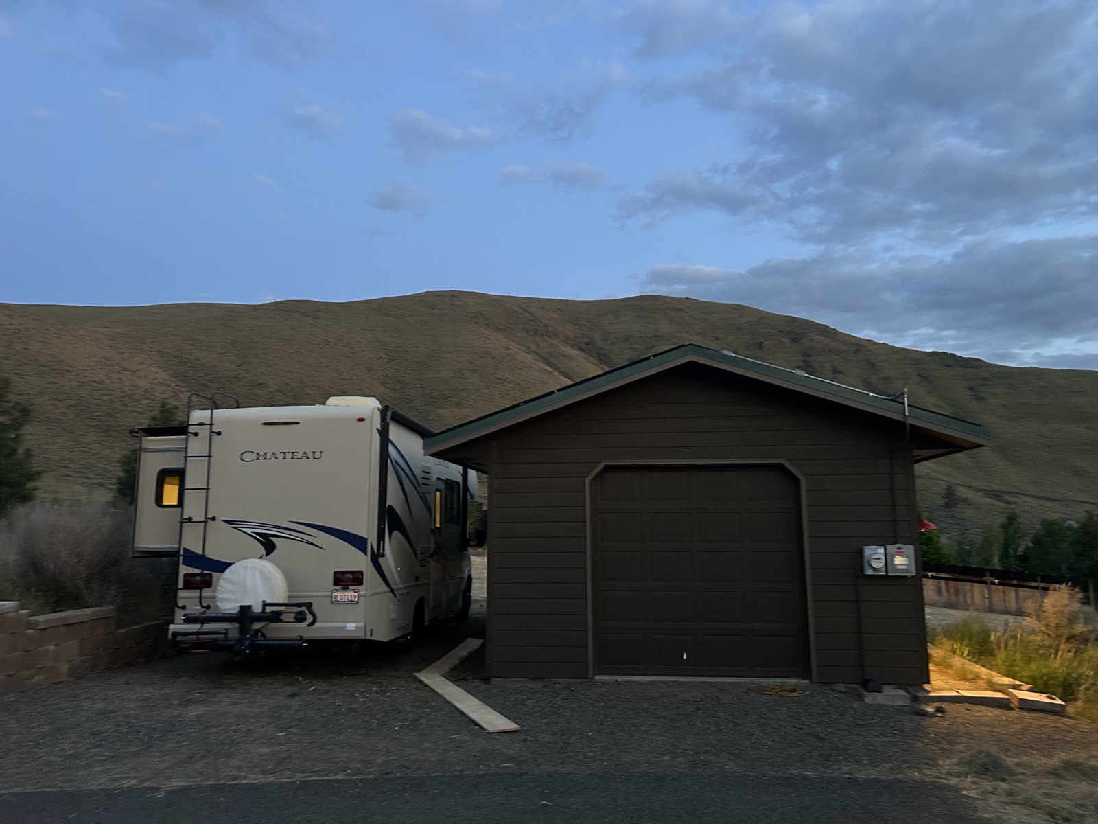Class C motorhome parked at the 30-amp RV hookup beside the detached garage at Canyon Basin House